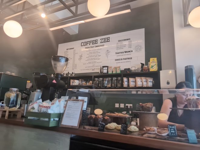 Wide view along the service counter with pastries under glass and the espresso machine